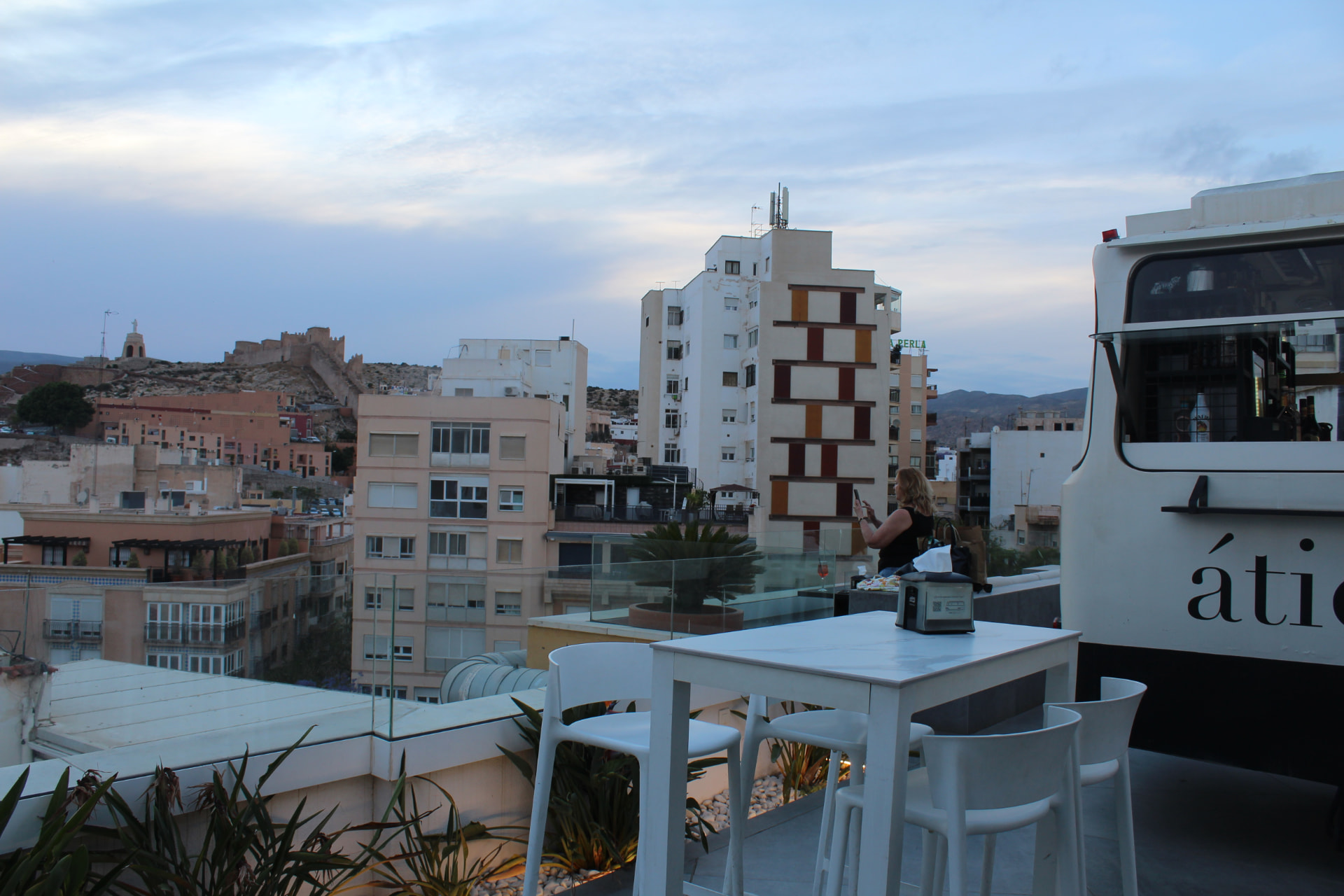 A rooftop terrace at dusk with the city and the Alcazaba beyond