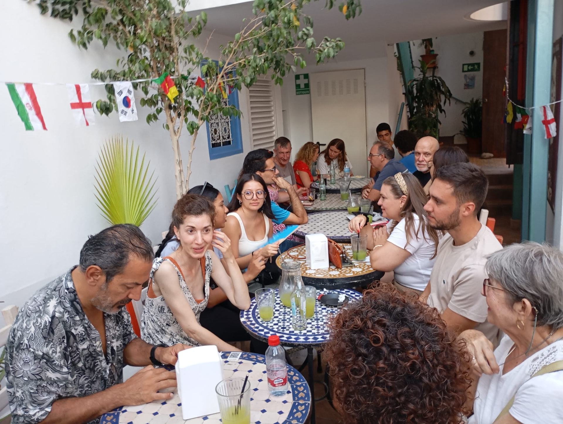 Guests deep in conversation at a language-exchange evening in an Andalusian courtyard
